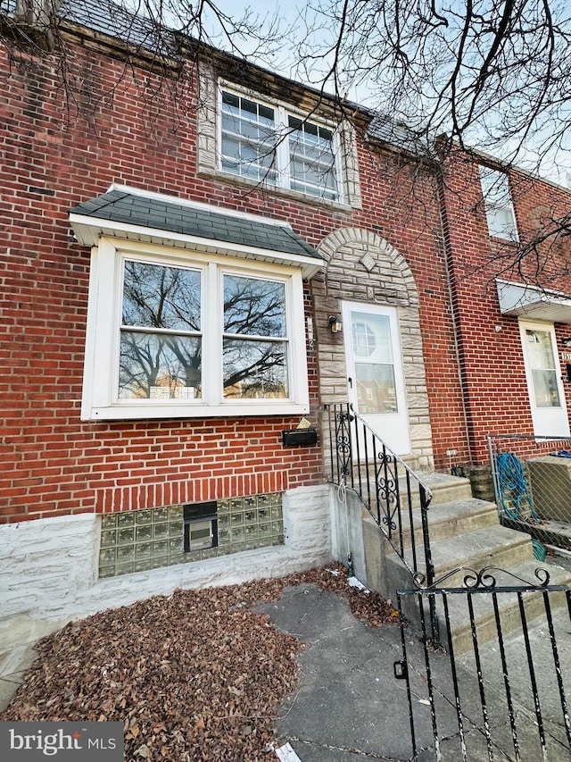 view of front of house featuring roof with shingles and brick siding