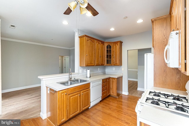 kitchen featuring white appliances, brown cabinets, light countertops, light wood-type flooring, and a sink