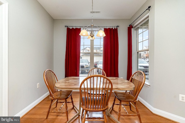 dining area with a notable chandelier, baseboards, visible vents, and light wood-style floors