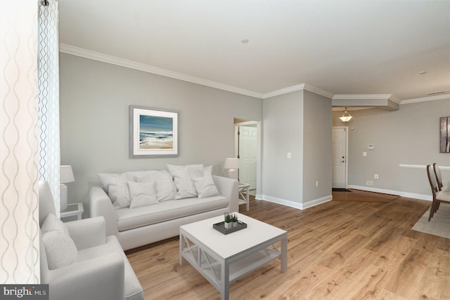 living area featuring crown molding, baseboards, and wood finished floors