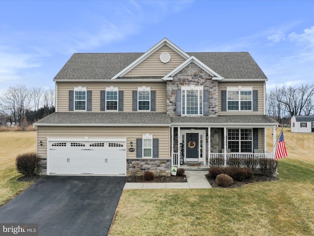 view of front of house with a porch, an attached garage, stone siding, driveway, and a front lawn