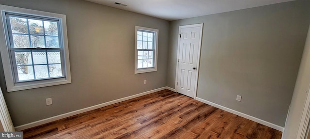 unfurnished room with baseboards, visible vents, and wood finished floors