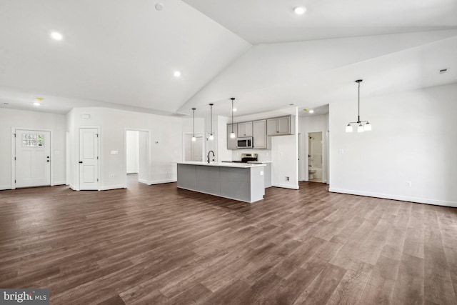 kitchen with a kitchen island with sink, stainless steel appliances, a sink, open floor plan, and dark wood-style floors