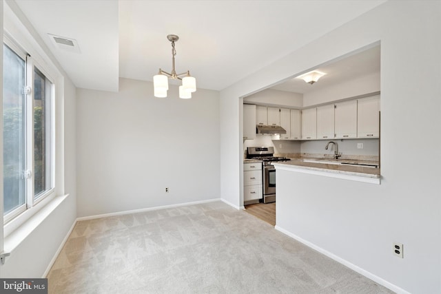 kitchen with light colored carpet, visible vents, stainless steel range with gas stovetop, a sink, and under cabinet range hood