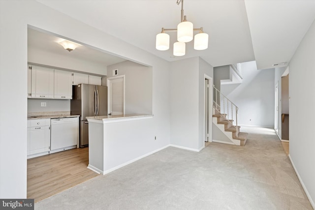 kitchen with white cabinetry, baseboards, light countertops, freestanding refrigerator, and dishwasher