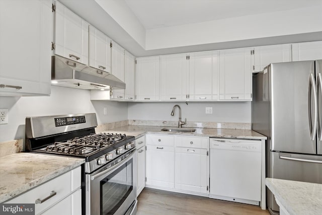 kitchen featuring light stone counters, under cabinet range hood, a sink, white cabinets, and appliances with stainless steel finishes