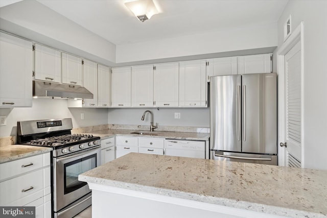 kitchen with white cabinets, light stone counters, stainless steel appliances, under cabinet range hood, and a sink