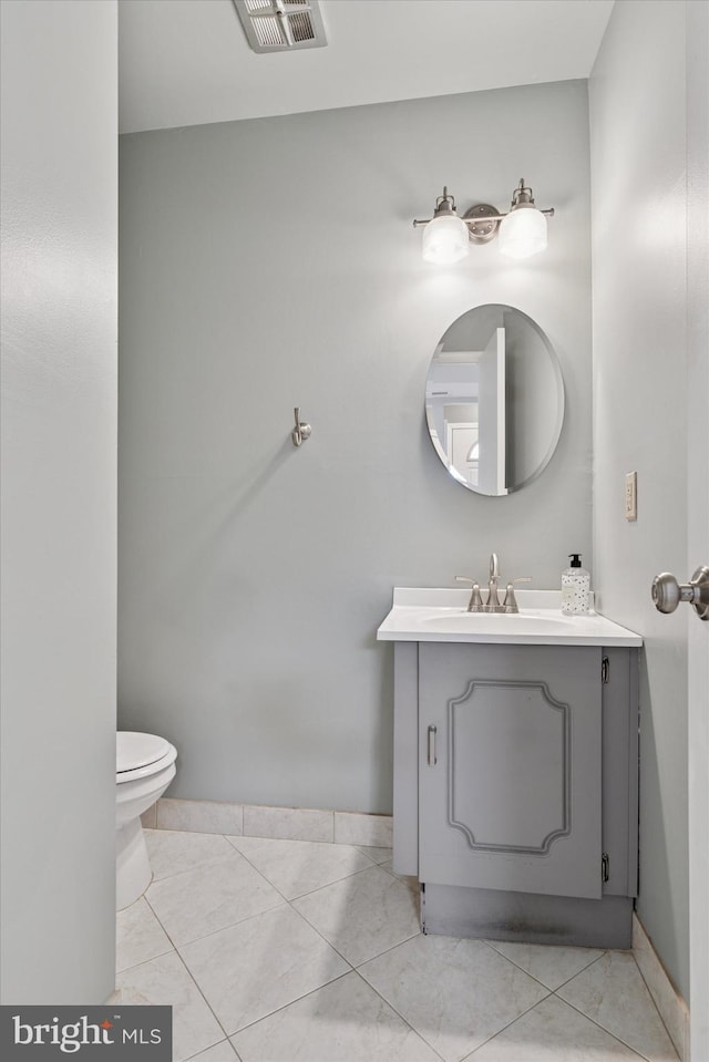 half bathroom featuring toilet, vanity, visible vents, and baseboards