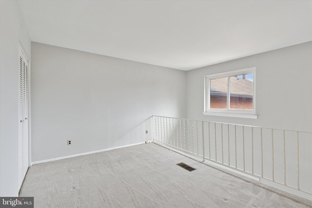 spare room with carpet, visible vents, and baseboards