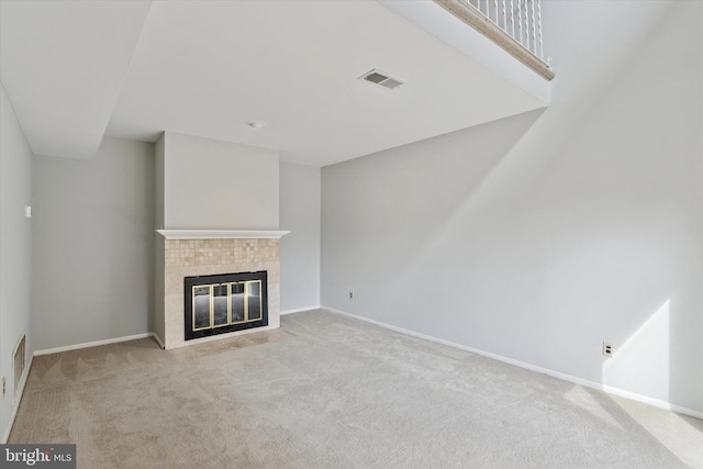 unfurnished living room featuring a tiled fireplace, carpet flooring, and visible vents