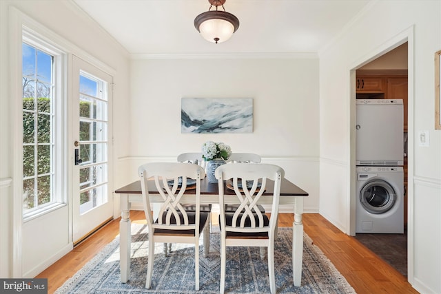 dining space with crown molding, baseboards, wood finished floors, and stacked washer / drying machine