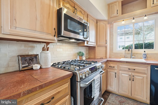 kitchen with light brown cabinets, stainless steel appliances, a sink, and decorative backsplash