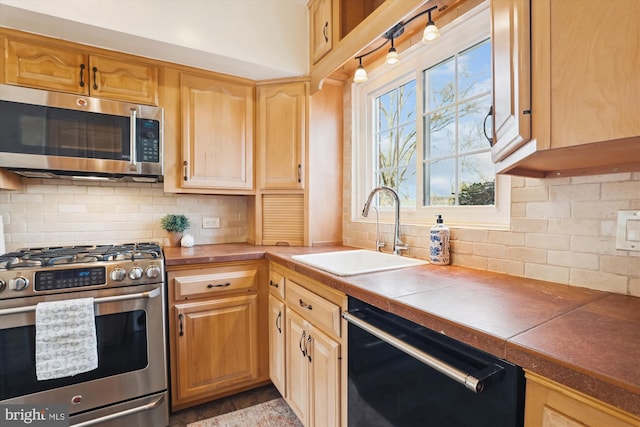 kitchen featuring stainless steel appliances, tile counters, a sink, and backsplash