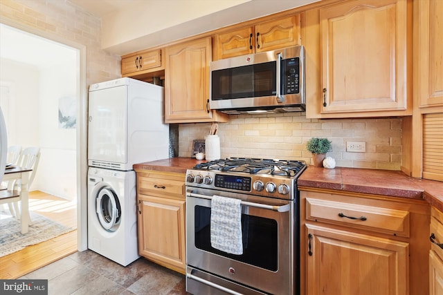 kitchen with stacked washing maching and dryer, tasteful backsplash, butcher block countertops, and stainless steel appliances