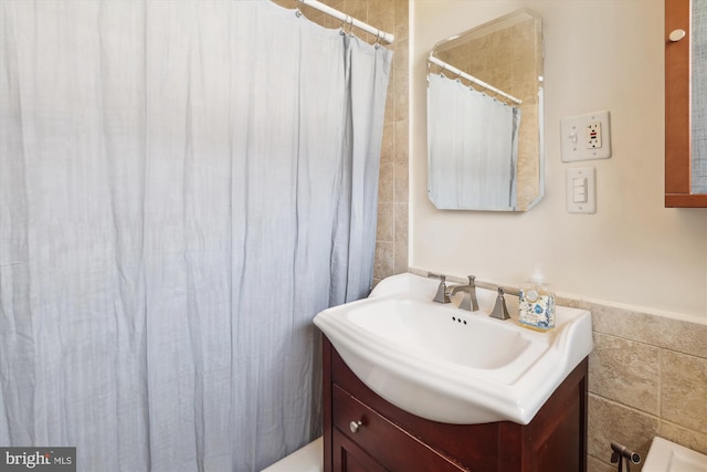 full bathroom featuring a shower with shower curtain, vanity, and tile walls