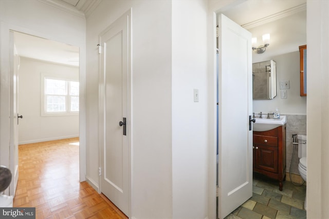 hallway with crown molding, tile walls, and a sink