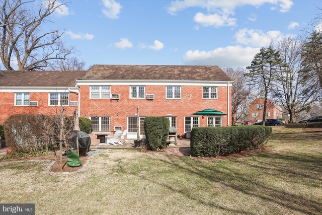 back of house with a yard, brick siding, and a patio