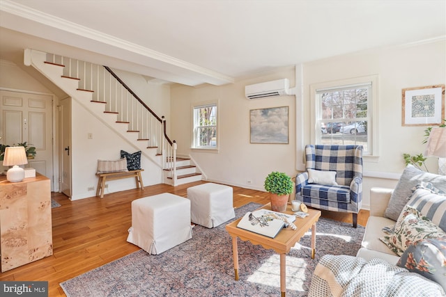 living room featuring baseboards, stairs, a wall mounted AC, light wood-type flooring, and crown molding