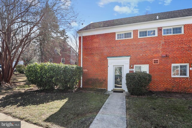 exterior space featuring brick siding and a front lawn