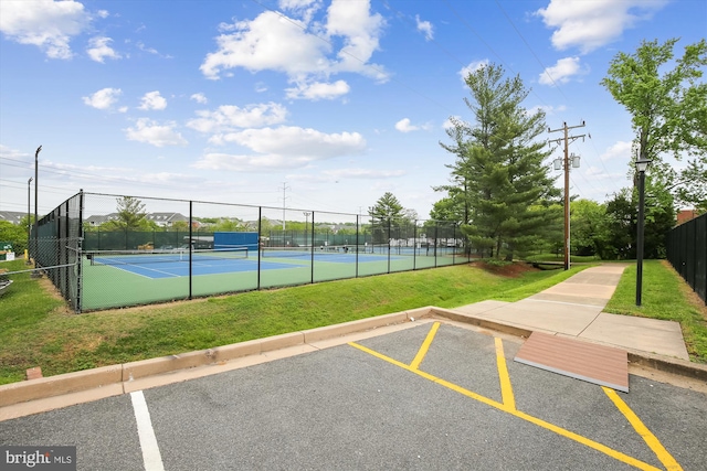 view of sport court with fence and a lawn