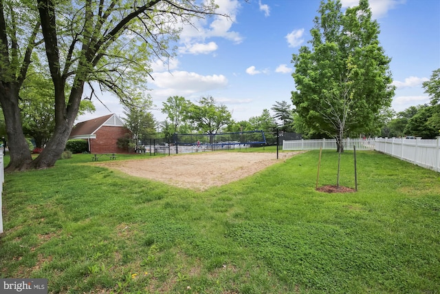 view of property's community featuring a yard, fence, and volleyball court