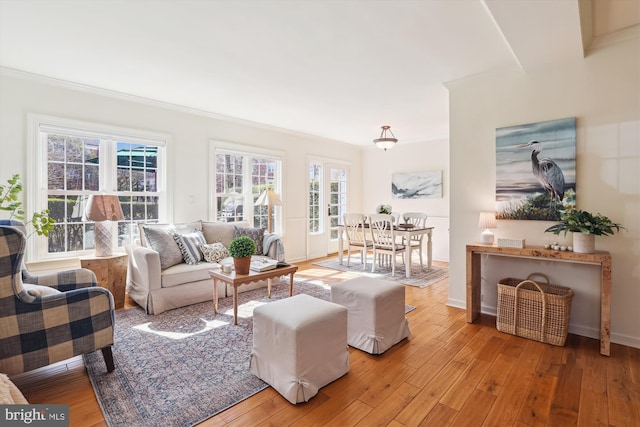 living room featuring light wood-type flooring, crown molding, and baseboards