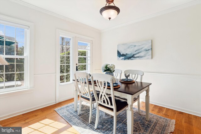 dining space with a healthy amount of sunlight, light wood-style flooring, and ornamental molding