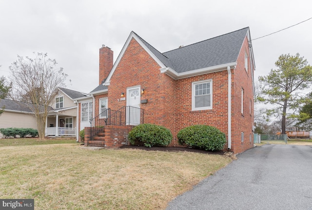 bungalow-style home with brick siding, a chimney, a front lawn, and roof with shingles