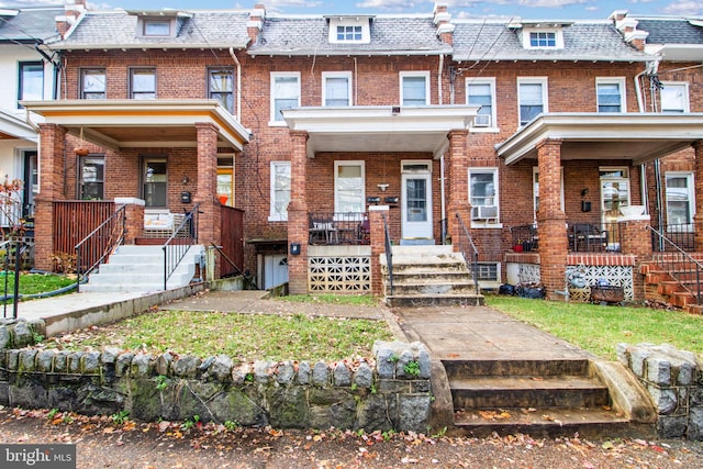 view of front of home featuring a porch, mansard roof, and brick siding