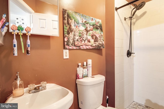 full bathroom with a sink, a tile shower, and toilet