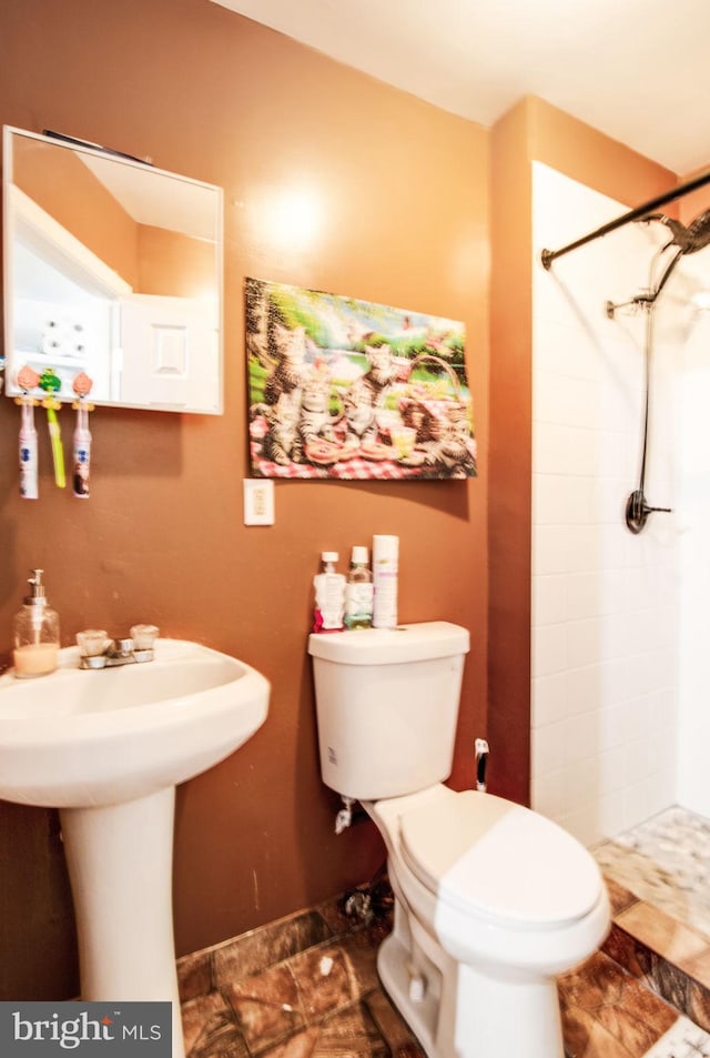 bathroom featuring toilet and a tile shower