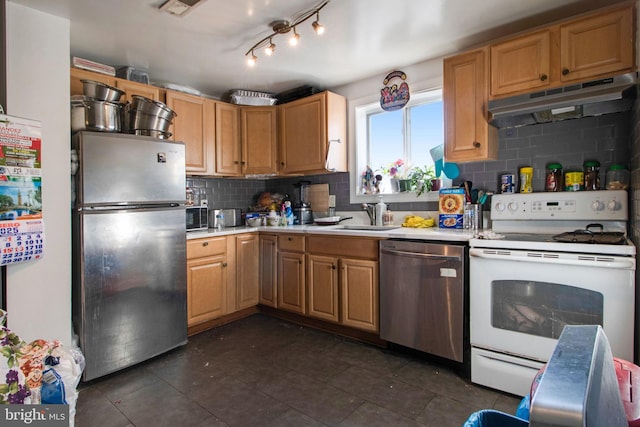 kitchen with under cabinet range hood, a sink, light countertops, appliances with stainless steel finishes, and tasteful backsplash