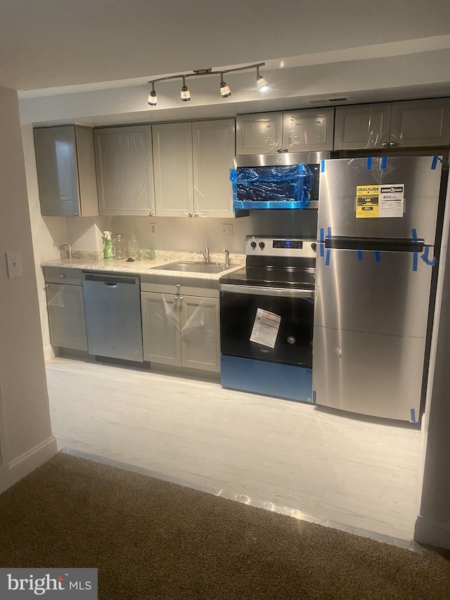 kitchen with appliances with stainless steel finishes, a sink, and gray cabinetry