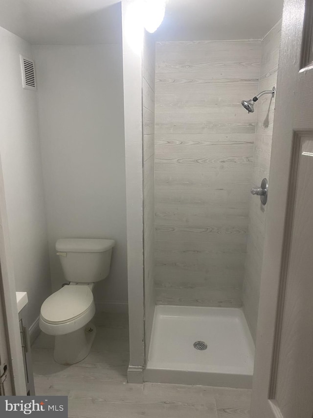 full bathroom featuring toilet, a stall shower, visible vents, and baseboards