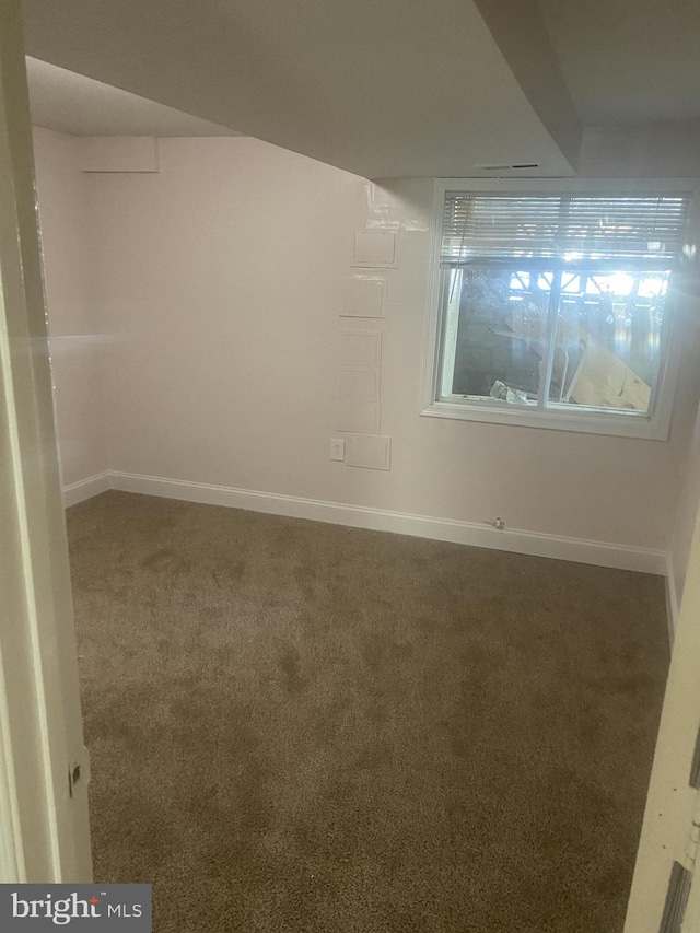 spare room featuring carpet flooring and baseboards