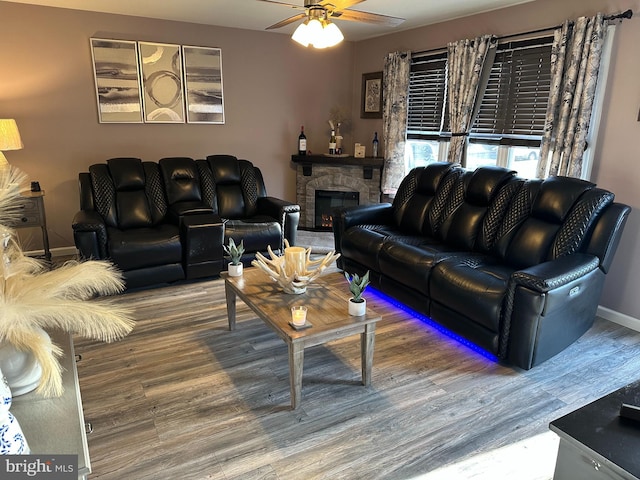 living area with ceiling fan, a fireplace, baseboards, and wood finished floors