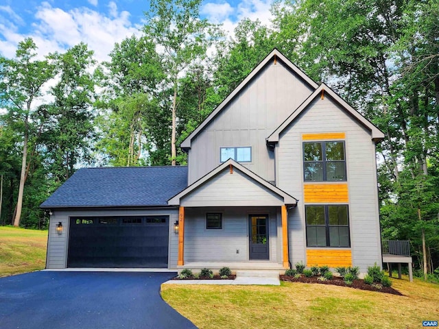 view of front facade with aphalt driveway, a front lawn, board and batten siding, and an attached garage