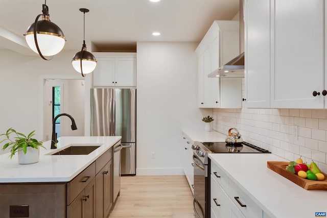 kitchen featuring a sink, exhaust hood, light countertops, appliances with stainless steel finishes, and backsplash