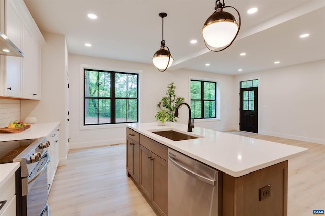 kitchen with light wood-style floors, stainless steel appliances, a sink, and light countertops