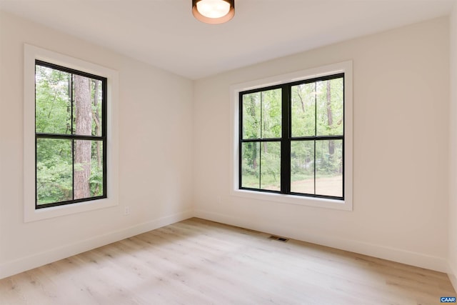 unfurnished room featuring a wealth of natural light, visible vents, and light wood-style floors