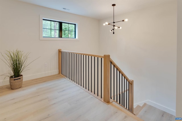 interior space with an inviting chandelier, visible vents, baseboards, and wood finished floors