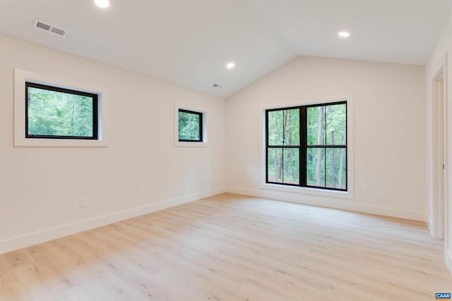 unfurnished room featuring lofted ceiling, light wood-style flooring, visible vents, and baseboards