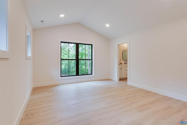 unfurnished room featuring lofted ceiling, light wood-style flooring, and baseboards