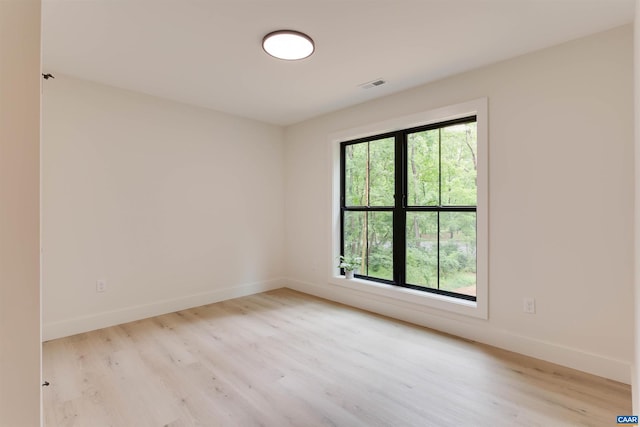 empty room with light wood-style flooring, visible vents, and baseboards