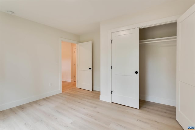 unfurnished bedroom featuring a closet, light wood-style flooring, and baseboards