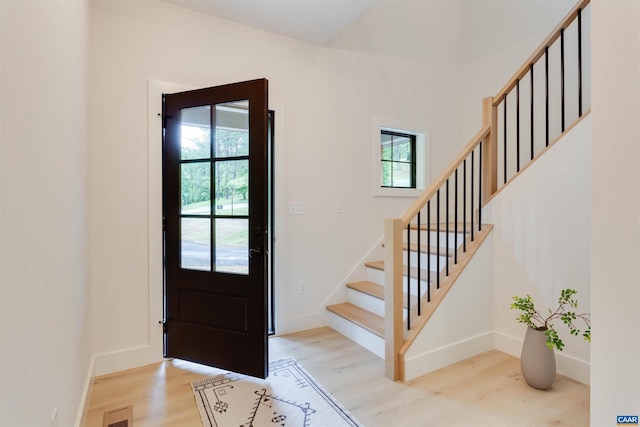 foyer with stairway, visible vents, light wood-style flooring, and baseboards