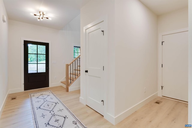 entryway with visible vents, light wood-style flooring, baseboards, and stairs