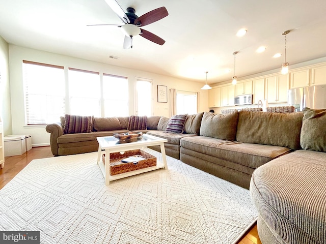 living area with light wood-type flooring, visible vents, ceiling fan, and recessed lighting