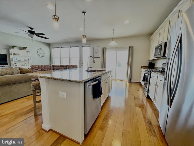 kitchen featuring a breakfast bar, light wood-style flooring, appliances with stainless steel finishes, white cabinetry, and a sink