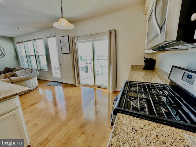 kitchen with open floor plan, light countertops, appliances with stainless steel finishes, light wood-type flooring, and decorative light fixtures